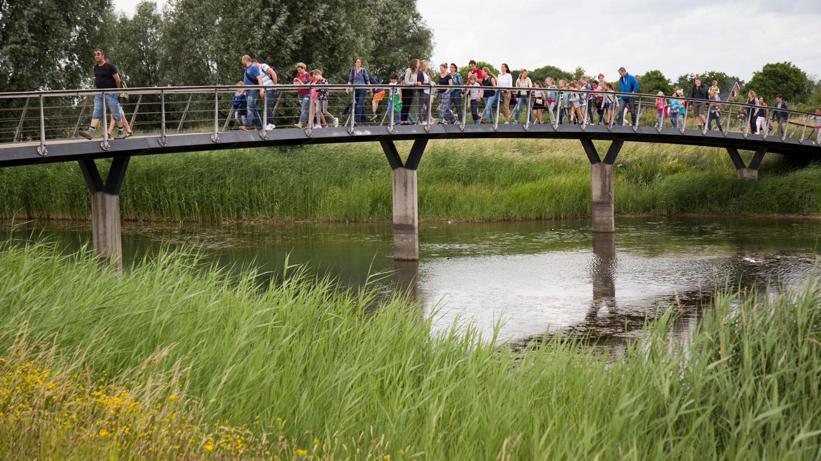 Volwassen en kinderen wandelen over een bruggetje