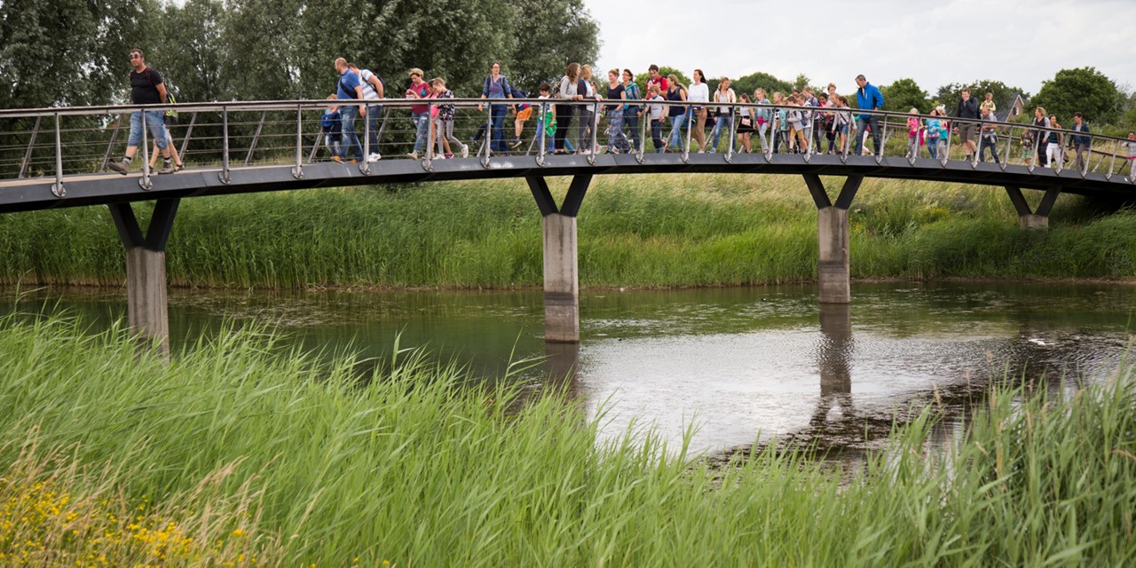 Volwassen en kinderen wandelen over een bruggetje