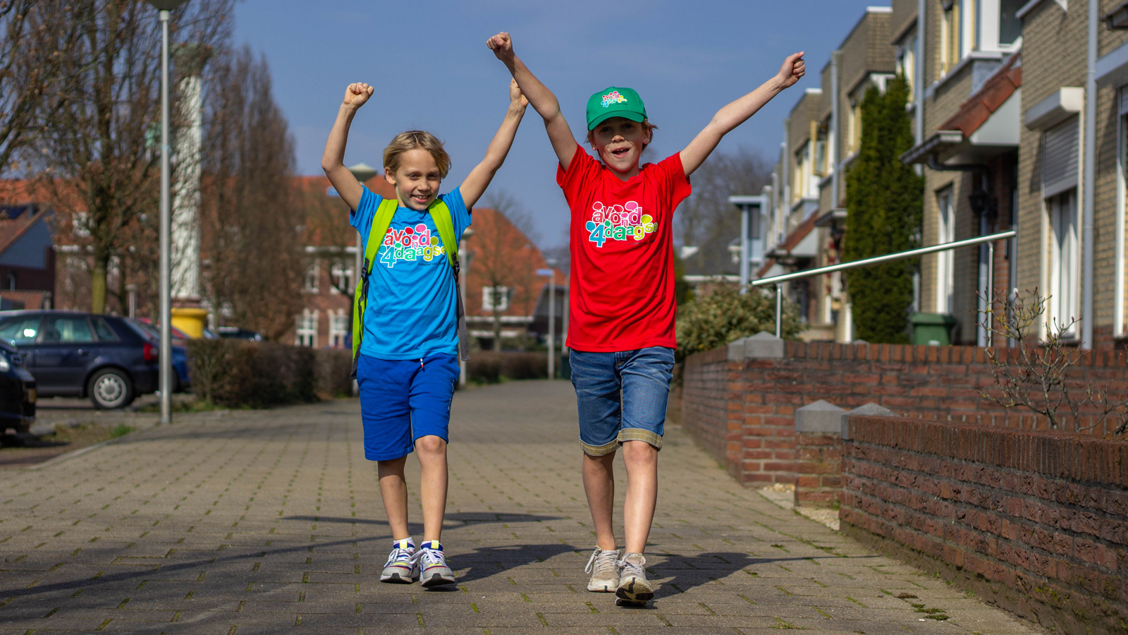 Twee jongens zwaaiend gekleed in een Avond4daagse shirt en pet