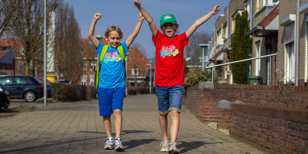 Twee jongens zwaaiend gekleed in een Avond4daagse shirt en pet