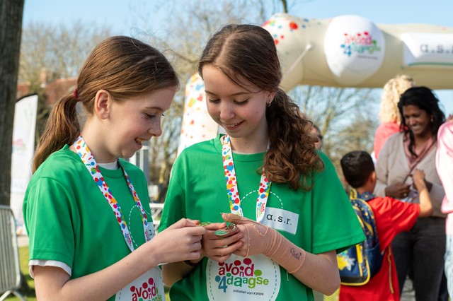 Twee kinderen kijken lachend naar elkaars Avond4daags medaille